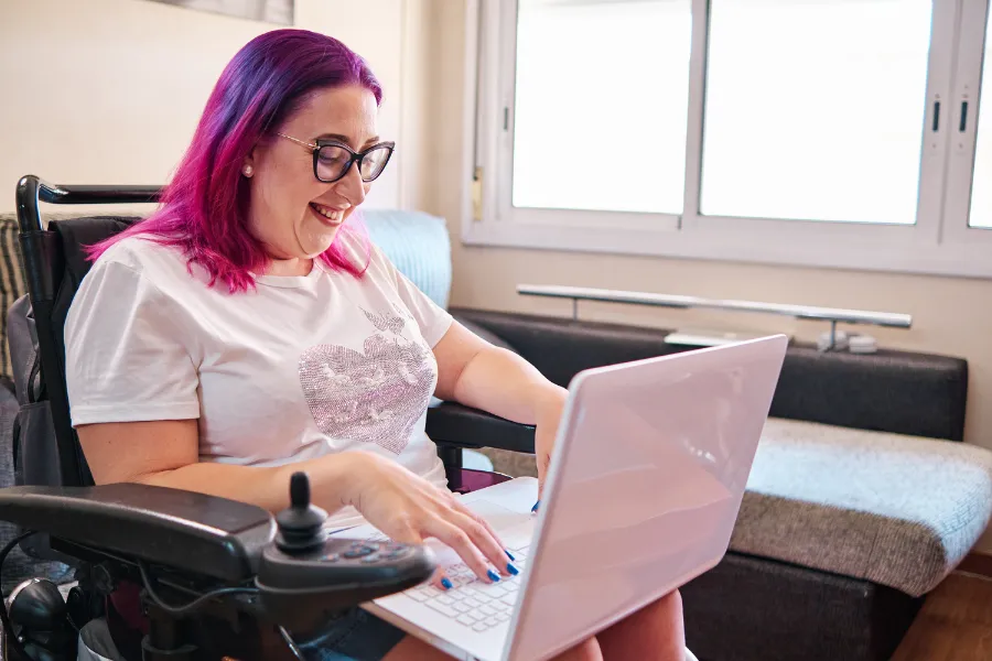 Woman smiling working on her laptop in her wheelchair
